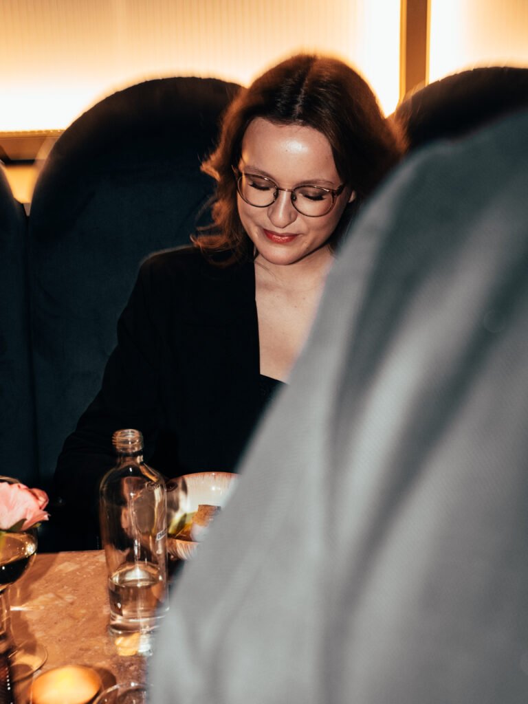 Marie Hendrickx die aan tafel zit en naar haar bord kijkt tijdens een sfeervol event.