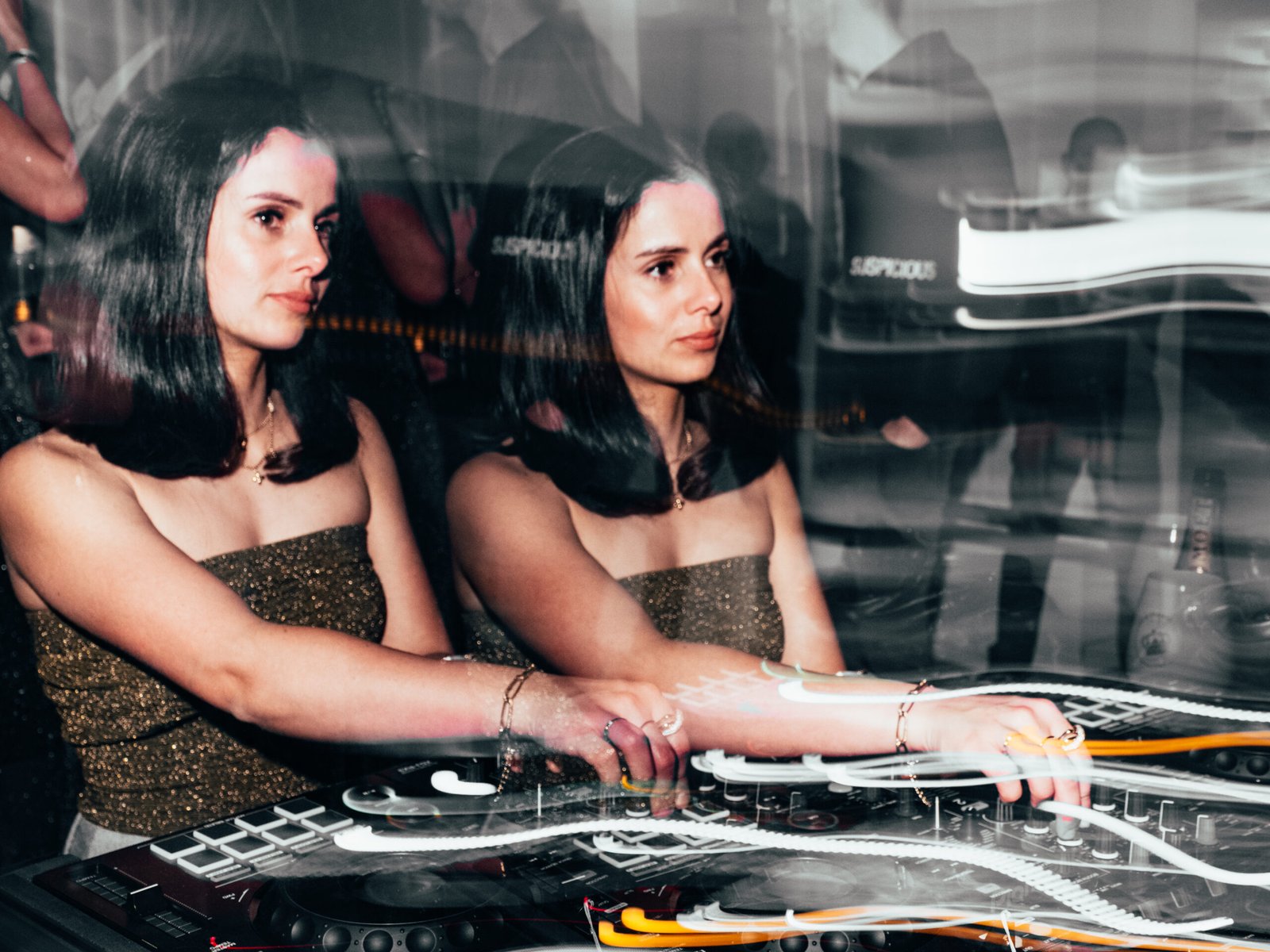 Vrouw achter de DJ-tafel tijdens CB Nights, met glittertop en lichteffecten door lange sluitertijd.