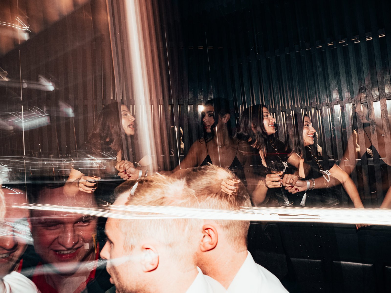 Reflecterende feestfoto van gasten tijdens CB Nights, met creatieve lichtstrepen en meerdere spiegelbeelden.