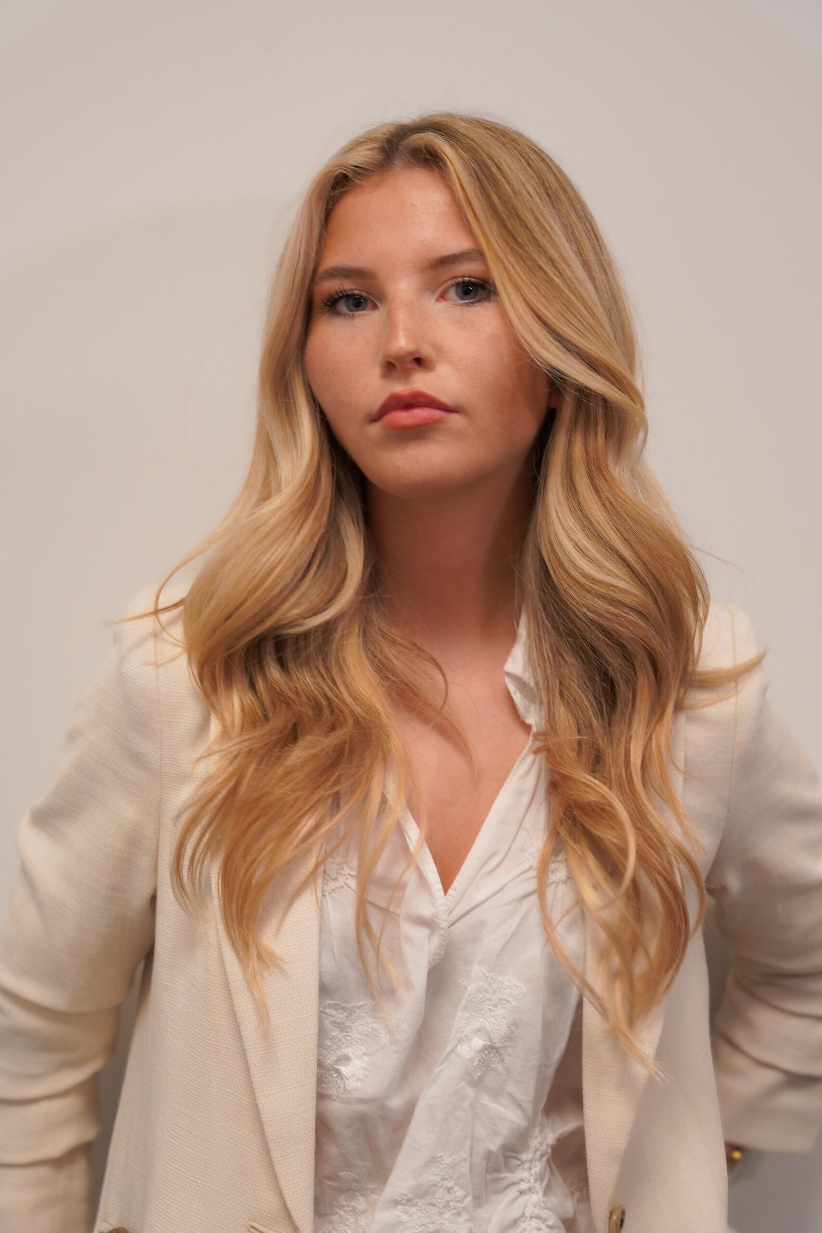 Professioneel portret van Fenna Timmermans met golvend haar en beige blazer.