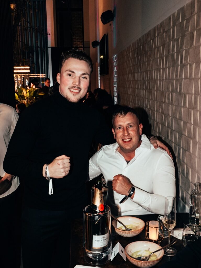 Alexander Taselaar en vriend poseren tijdens diner-event met champagne en feestelijke sfeer.